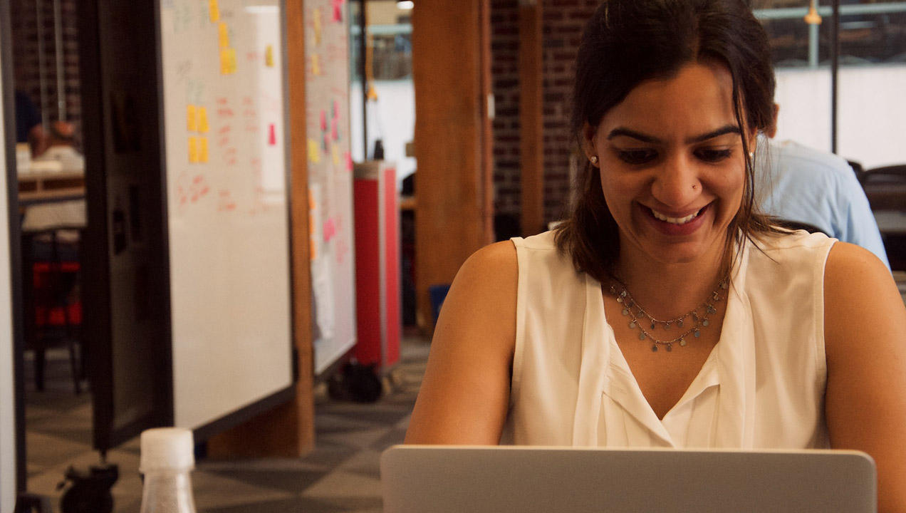 Akriti typing and smiling at her desk