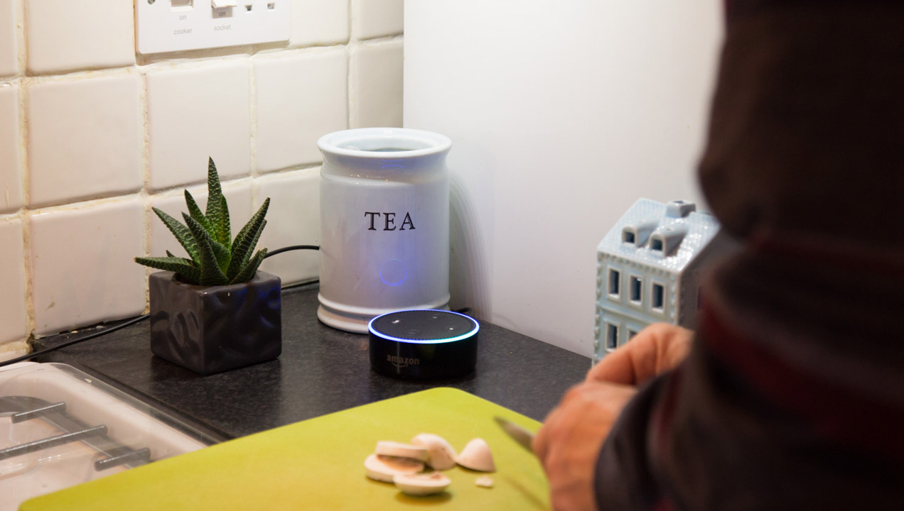 A person cooking and listening to the recipe on a voice assistant