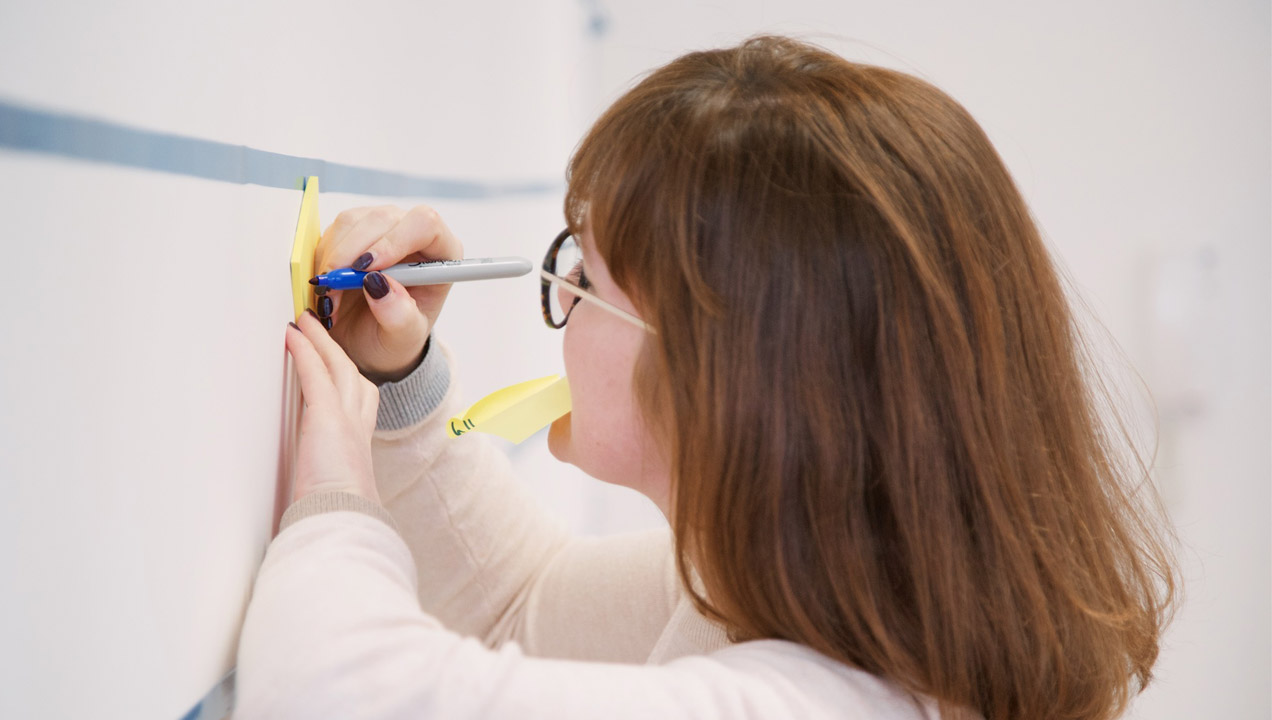 A person writing on a post-it note