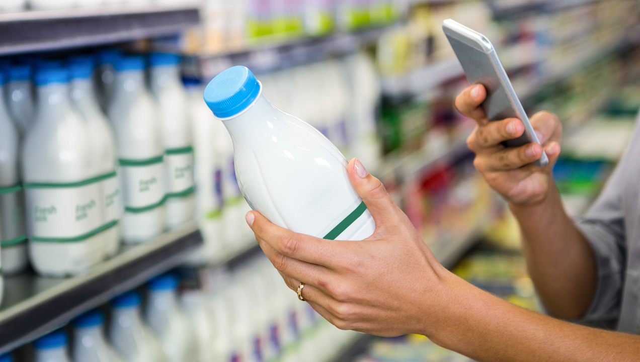 A customer scanning a bottle of milk with her phone using a scanning app