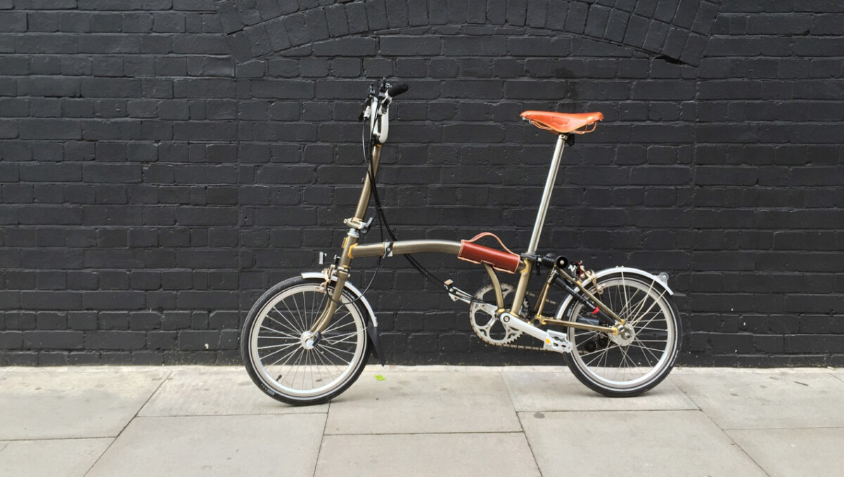 A Brompton bike in front of a wall, unfolded