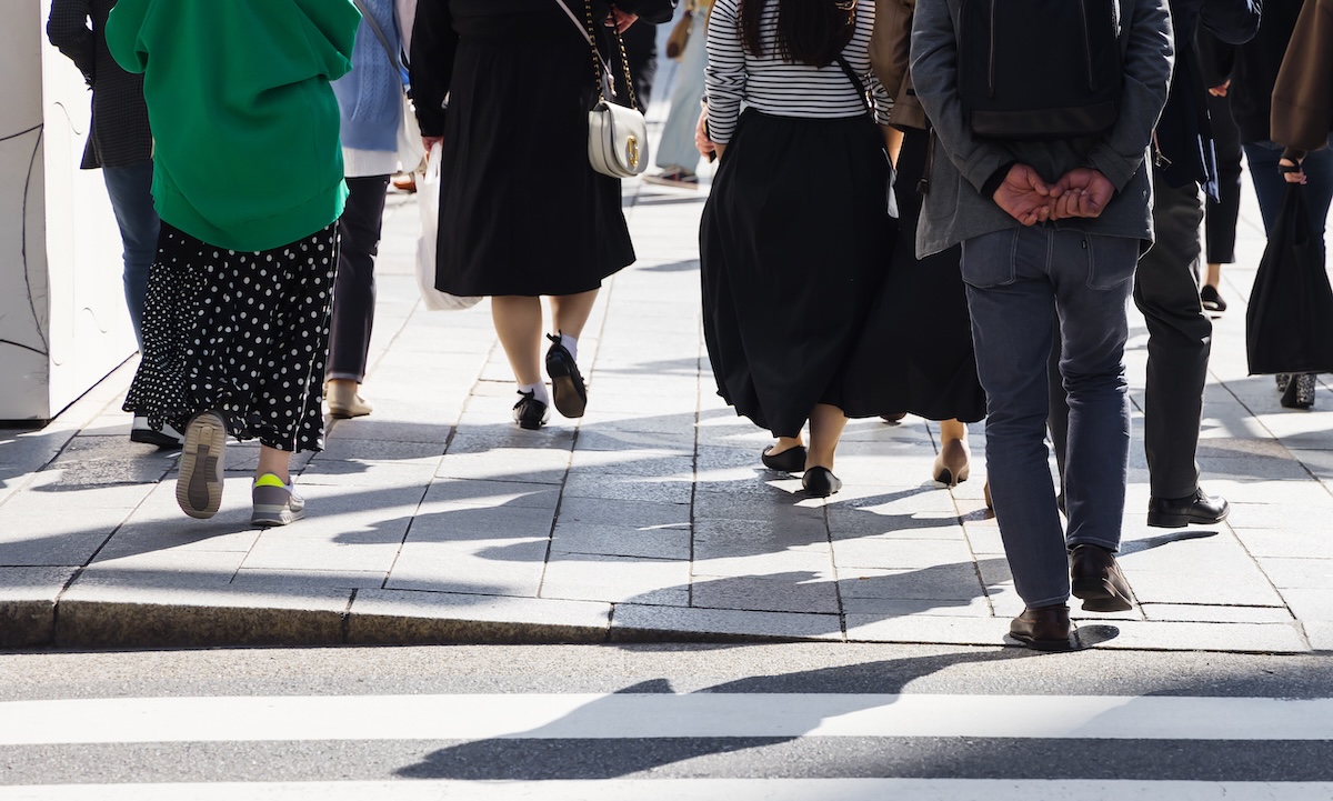 Image of people's legs at a street crossing with a cut curb. 